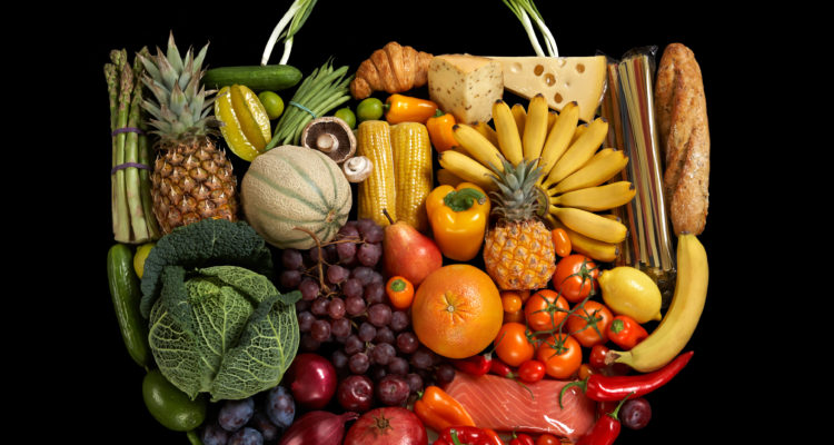 Organic fruits and vegetables assembled to resemble a shopping bag