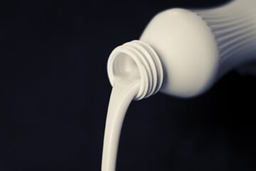 Milk being poured from a bottle. Black background-Pure & Eco India