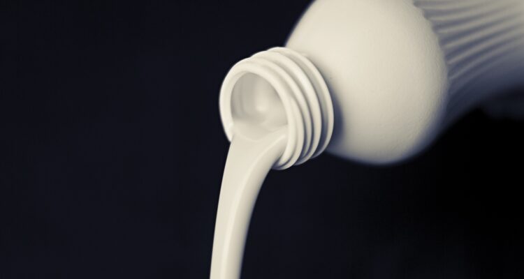 Milk being poured from a bottle. Black background-Pure & Eco India